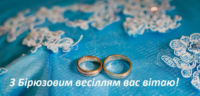 Золоті кільця на блакитній тканині з вітанням.