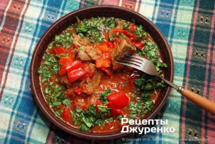 Смачне м'ясне рагу з овочами та зеленню в глибокій тарілці.